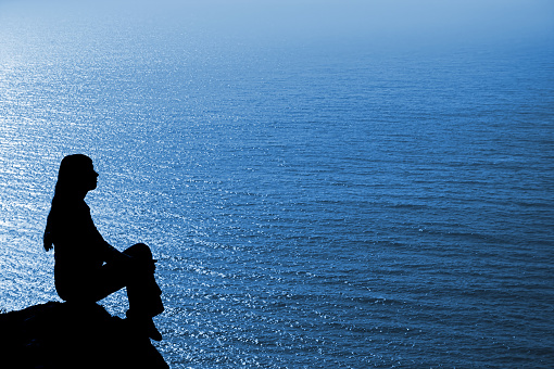 Meditating woman silhouette against seascape