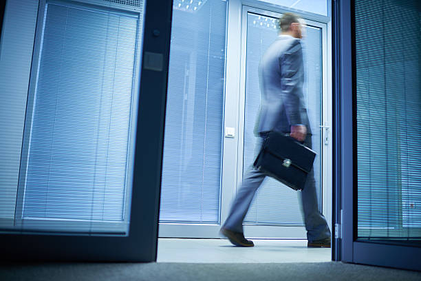 Walking past office Businessman walking along office corridor and passing by open door  office leave stock pictures, royalty-free photos & images