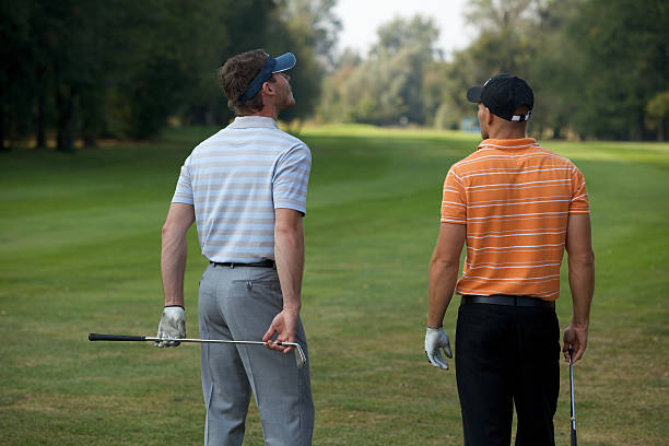 istock Young men standing in golf course with sticks, rear view 471951182