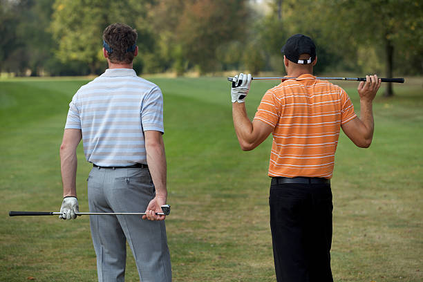 istock Young men standing in golf course with sticks, rear view 471951184