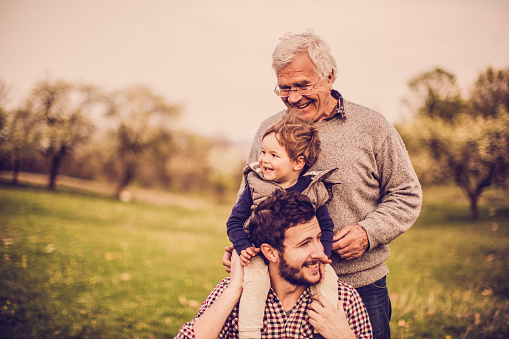 Photo of smiling little boy with his father and grandfather, enjoying in the amazing nature
