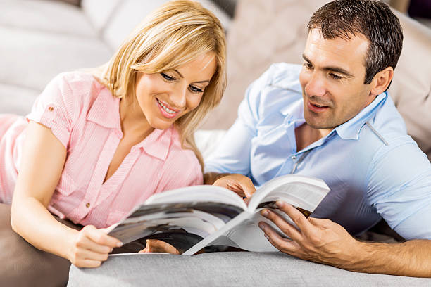 Couple reading a magazine at home.