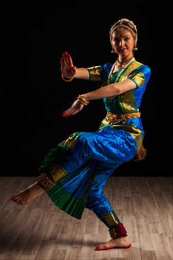 Young beautiful woman dancer exponent of Indian classical dance Bharatanatyam in Shiva pose