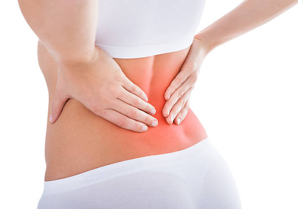 Woman suffering from lower back pain in white Young Woman With Pain In Her Back Over White Background lower back pain stock pictures, royalty-free photos & images