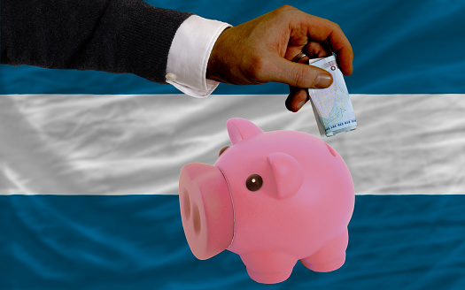 Man putting euro into piggy rich bank and national flag of el salvador in foreign currency because of insecurity and inflation