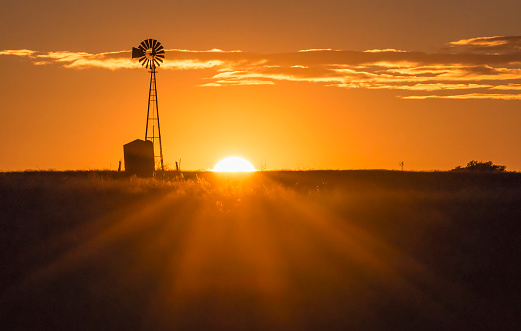The sun sets near a windmill in the Texas Hill Country