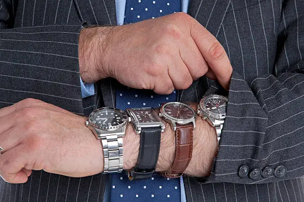 Businessman with four wrist watches checking the time. Good image for time related themes.