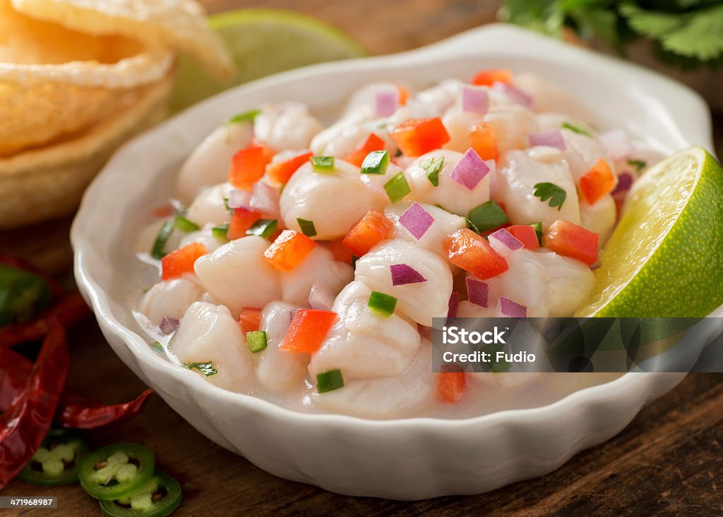 A white dish of ceviche garnished with a slice of lime A freshly made scallop ceviche with red onion, cilantro, red pepper, lime, and serrano pepper. Seviche Stock Photo