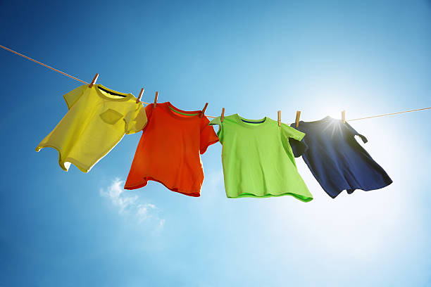 Clothesline and laundry T-shirts hanging on a clothesline in front of blue sky and sun hanging fabric stock pictures, royalty-free photos & images