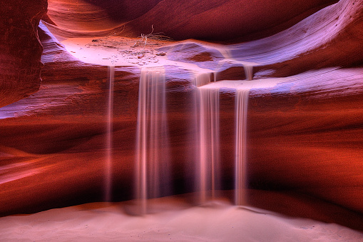 Sand falling from the red rock walls within Antelope Canyon, Page, Arizona
