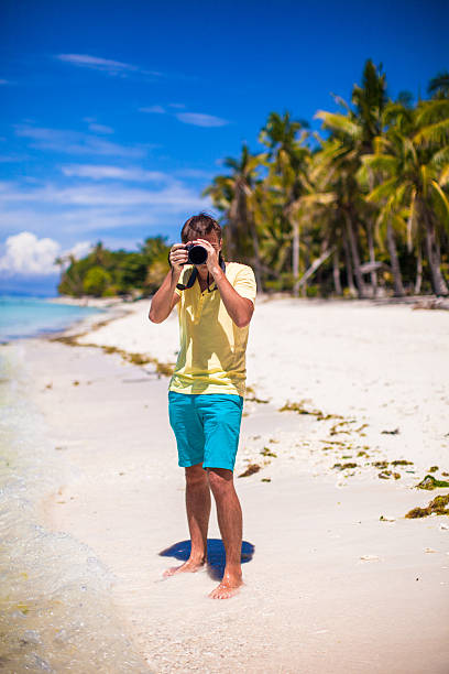 istock Young man with photocamera on beautiful white sandy beach 471975889