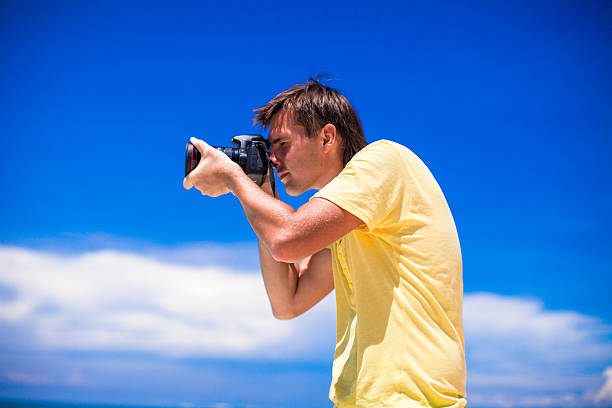 istock Young man with a camera on white sand beach 471976075