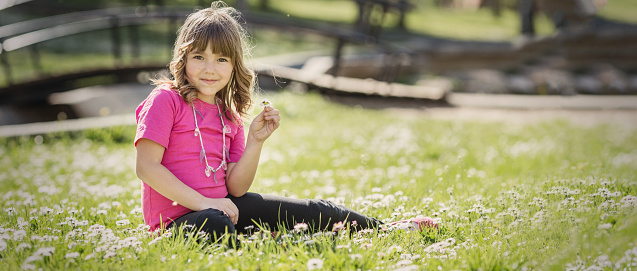 Little girl sitting on the grass in the park