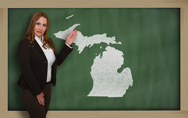 istock Teacher showing map of michigan on blackboard 471978507