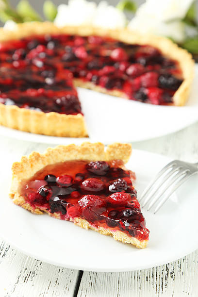 istock Fresh berry tart on plate on white wooden background 471984886
