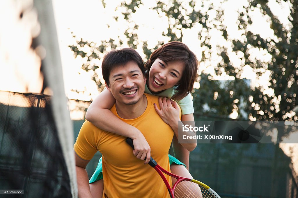 Boyfriend holding his girlfriend next to the tennis net Vitality Stock Photo