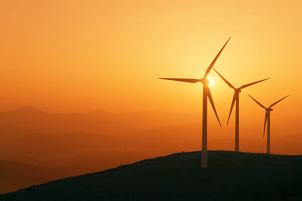 wind turbines silhouette on mountain at sunset stock photo