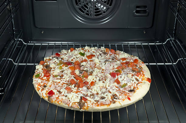 Raw and frozen pizza in the oven. stock photo