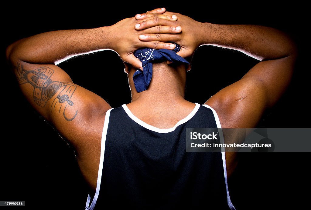 Man Being Arrested Black man with hands up behind his back is under arrest.  The man is wearing a bandana on a black background.  He is holding his hands up in a surrendering gesture while being arrested perhaps because of a crime or racial profiling. Racial Profiling Stock Photo