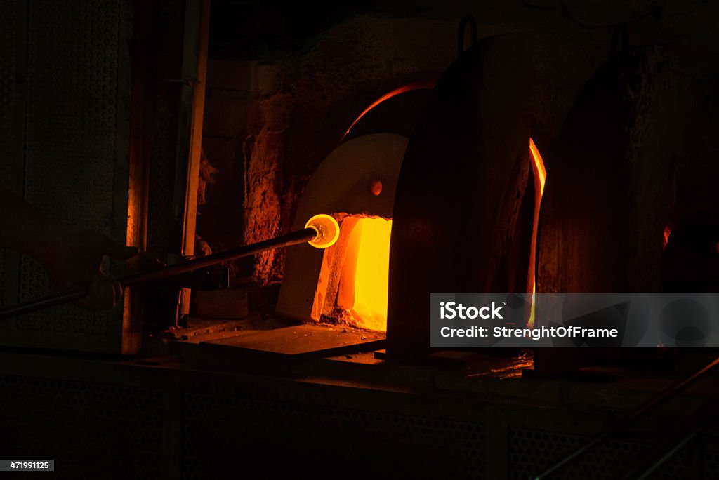 Glass Works Caucasian male working with melting glass at his shop Glass Blower Stock Photo