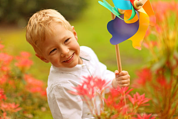istock Smiling Boy Playing with Colorful Pinwheel Toy in a Park 471991184