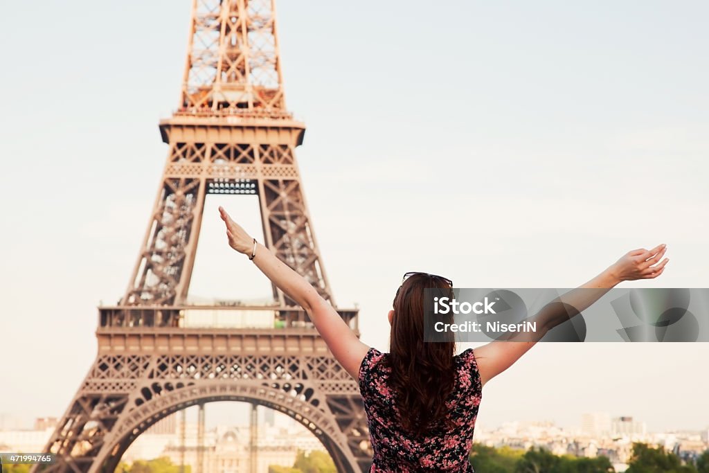 Young happy woman facing the Eiffel Tower, Paris, France Young attractive happy woman with hands up facing the Eiffel Tower in Paris, France Eiffel Tower - Paris Stock Photo