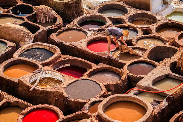 Man working in traditional Moroccan leather tanneries, medina Fez, Morocco. Fez is the second largest city of Morocco, and is a UNESCO World Heritage Site. The city has been called the "Mecca of the West" and the "Athens of Africa".http://bem.2be.pl/IS/morocco_380.jpg