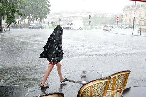 Young girl walking at summer rain in the city