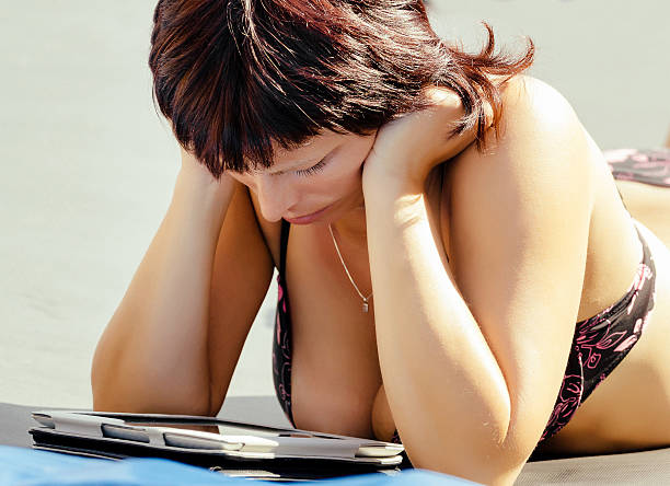 istock busty woman with swimsuit reading news on tablet 472000305