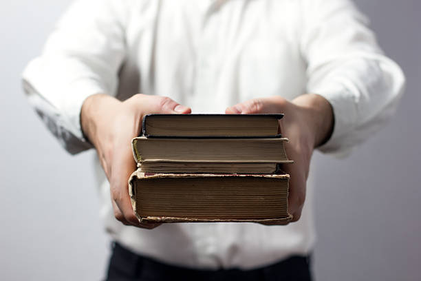 istock Hands holding books isolated on grey background 472002446