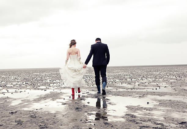 Bride and groom go in rubber boots walk in the Wadden Sea