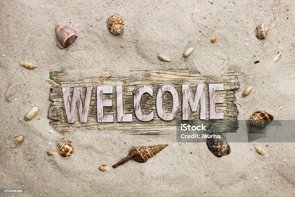 Welcome sign by seashells on the beach Welcome sign with sand beach border and seashells 2015 Stock Photo