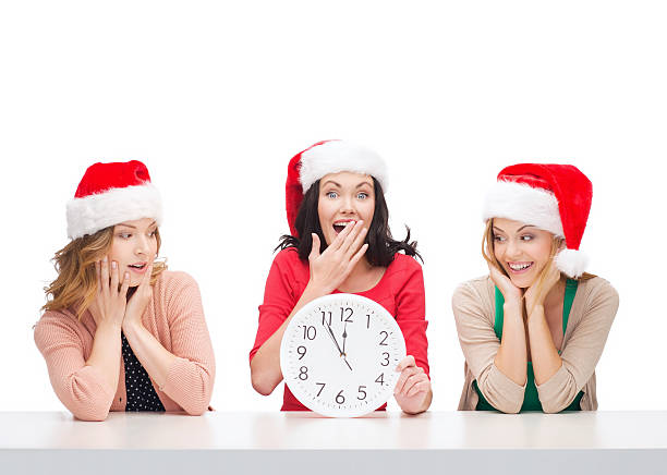 istock women in santa helper hats with clock showing 12 472008431