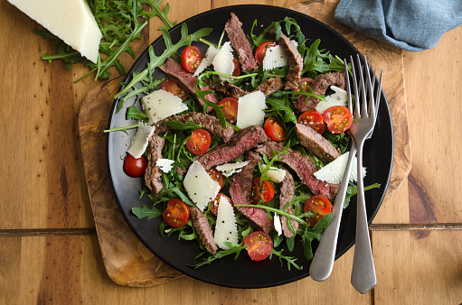 Seared steak, rocket and tomato salad topped with shaved Parmesan