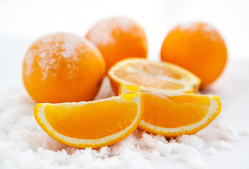 Oranges and slices of orange on the snow, close-up