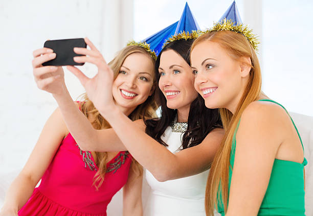 istock three smiling women in hats having fun with camera 472015901