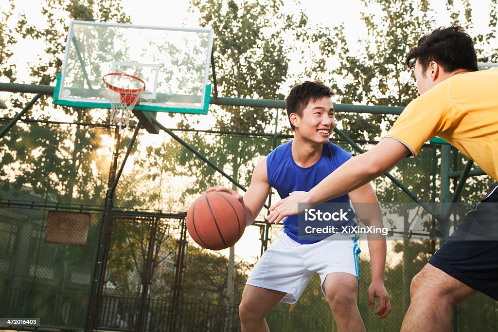 Two young men playing basketball on a public outdoor court Two street basketball players on the basketball court Basketball - Sport Stock Photo