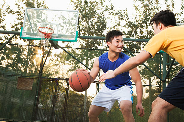 Two young men playing basketball on a public outdoor court stock photo