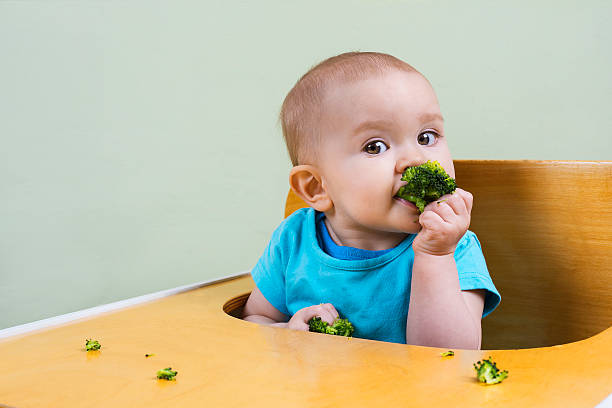 istock beautiful baby eating broccoli 472020972