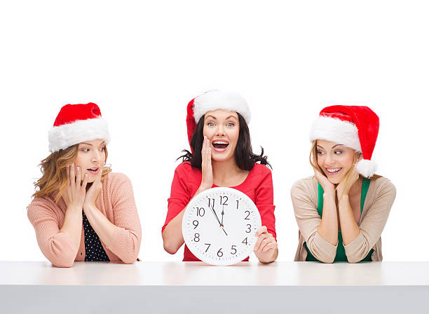 istock women in santa helper hats with clock showing 12 472021115