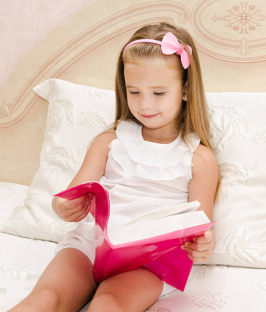 istock Cute little girl reading a book 472022501