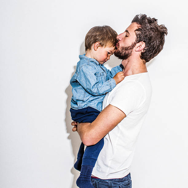 Father and son Photo portrait of father and son, isolated on white background. Father holding his son and kissing him in a forehead fashionable dad stock pictures, royalty-free photos & images