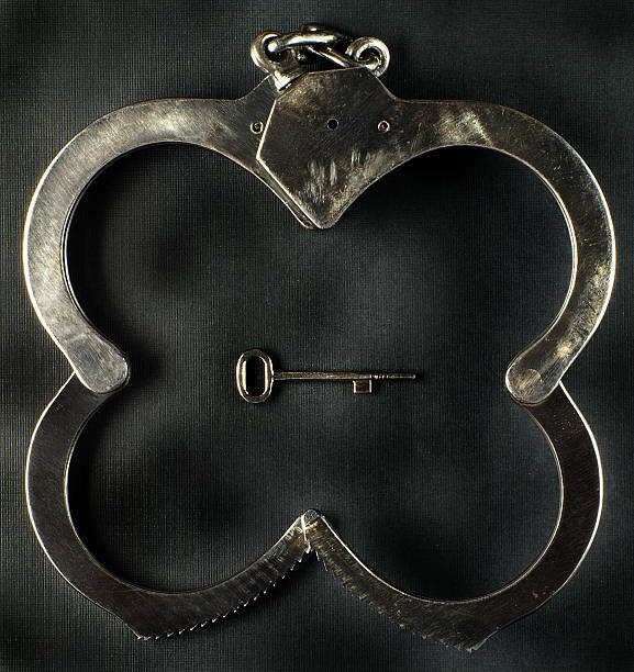 Steel police handcuffs in the shape of a happy clover stock photo