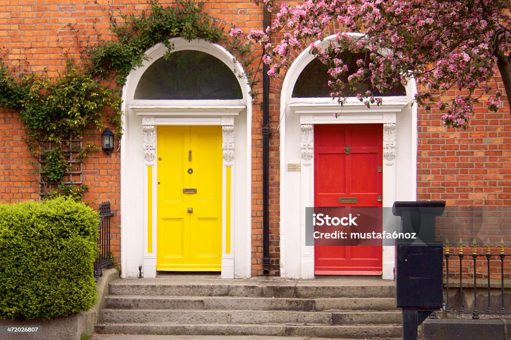Yellow and red two Dublin doors in spring Yellow and red two Dublin doors with pink blooms and green ivies on the brick wall, stairs at the front in spring. Two Objects Stock Photo