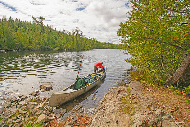 Couple carrying a red canoe near a lake.