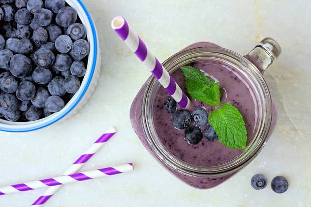 heidelbeer-smoothie luftaufnahme auf weißem marmor - blueberry smoothie glass striped stock-fotos und bilder