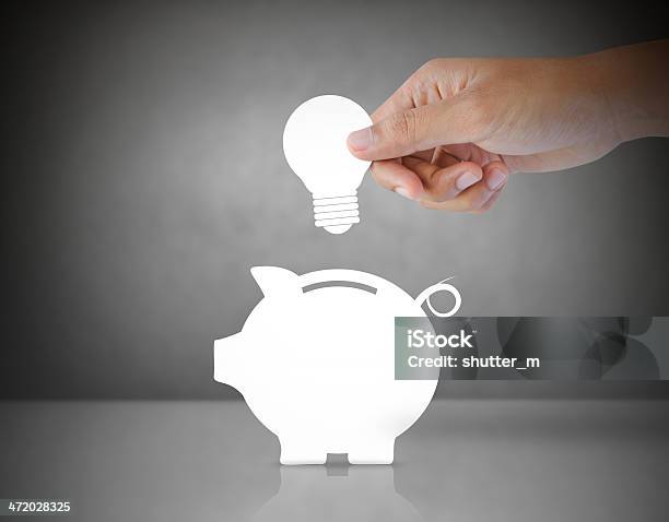 Male Hand Putting Light Bulb Into A Piggy Bank Stock Photo - Download Image Now - Light Bulb, Coin Bank, Piggy Bank