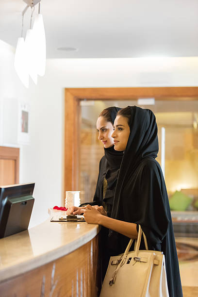 traditionell gekleideten nahen osten frauen, die beim check-in am empfang - hotel reception hotel receptionist health spa stock-fotos und bilder