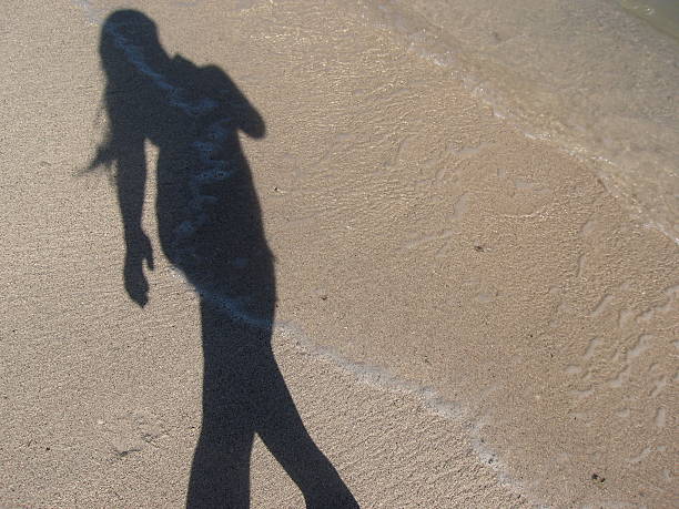 Shadow of Girl Walking on Beach stock photo