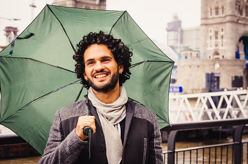 Young Man With Umbrella Near Tower Bridge In London